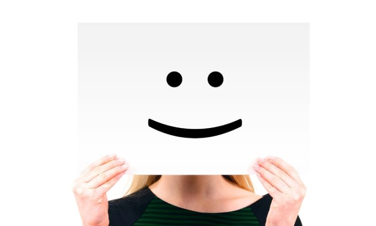 Personne qui tient une pancarte avec un sourire dessiné dessus
