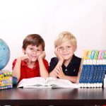 Deux jeunes étudiants entourés de livres qui sourient.