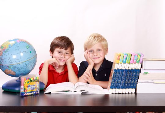Deux jeunes étudiants entourés de livres qui sourient.