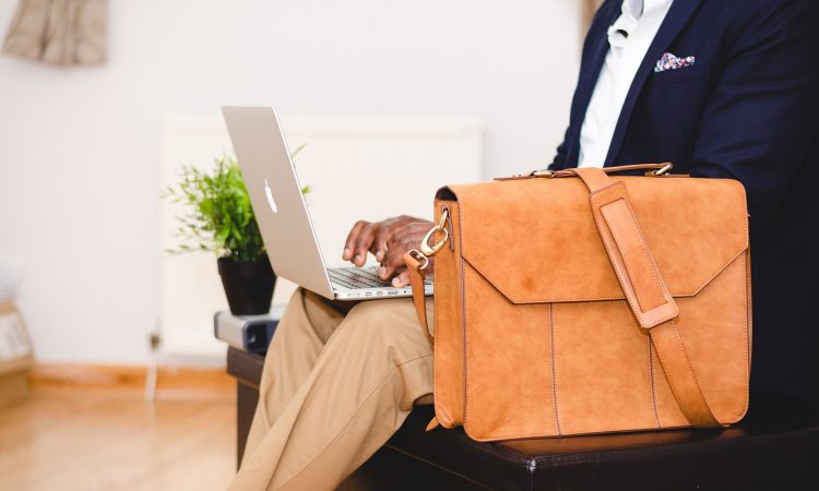 Homme avec une valise qui regarde son ordinateur.