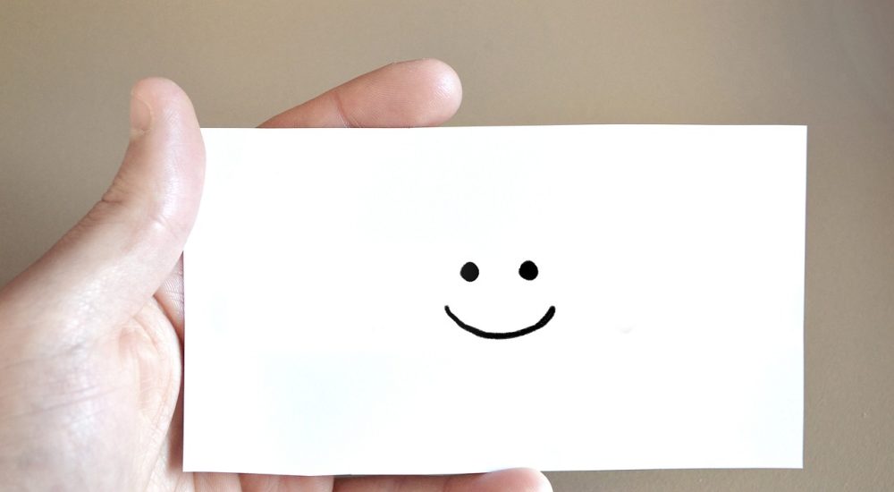 Personne qui tient une carte sourire dans ses mains