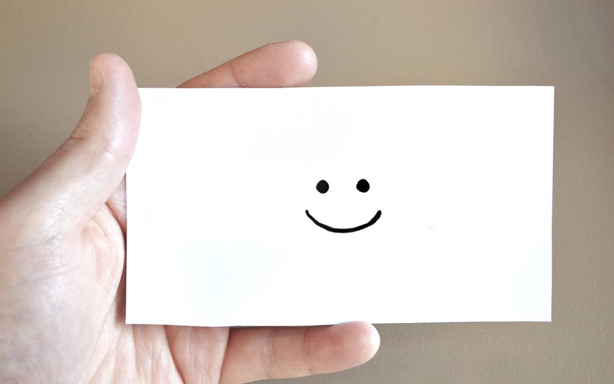 Personne qui tient une carte sourire dans ses mains