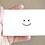 Personne qui tient une carte sourire dans ses mains