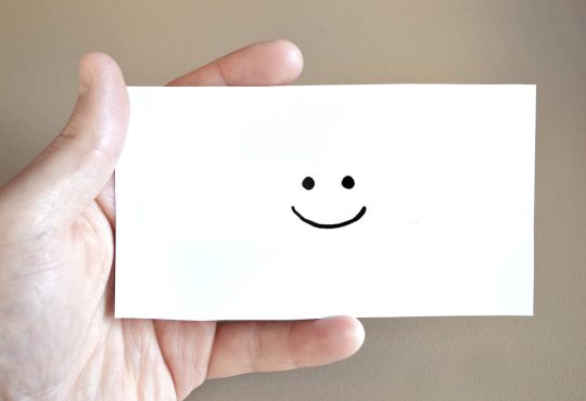 Personne qui tient une carte sourire dans ses mains