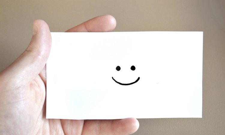 Personne qui tient une carte sourire dans ses mains