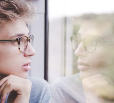 Jeunes homme qui regarde par la fenêtre